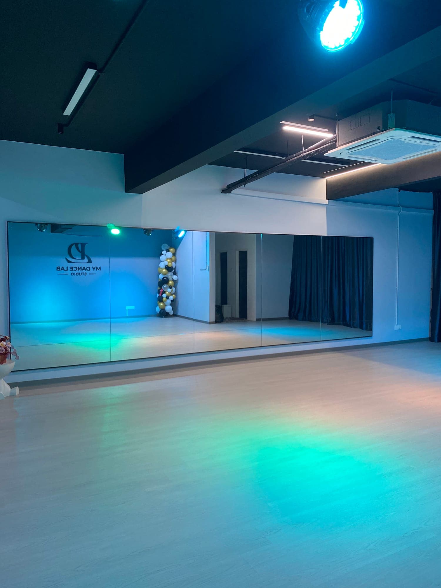 The studio floor washed in blue and green stage light in front of the mirror wall