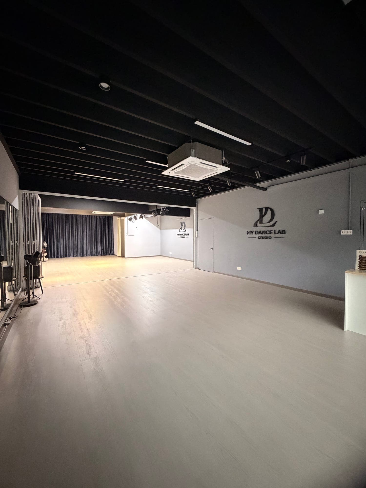 The empty Alma studio: a long light-grey floor, mirrors along the left wall and curtains at the far end