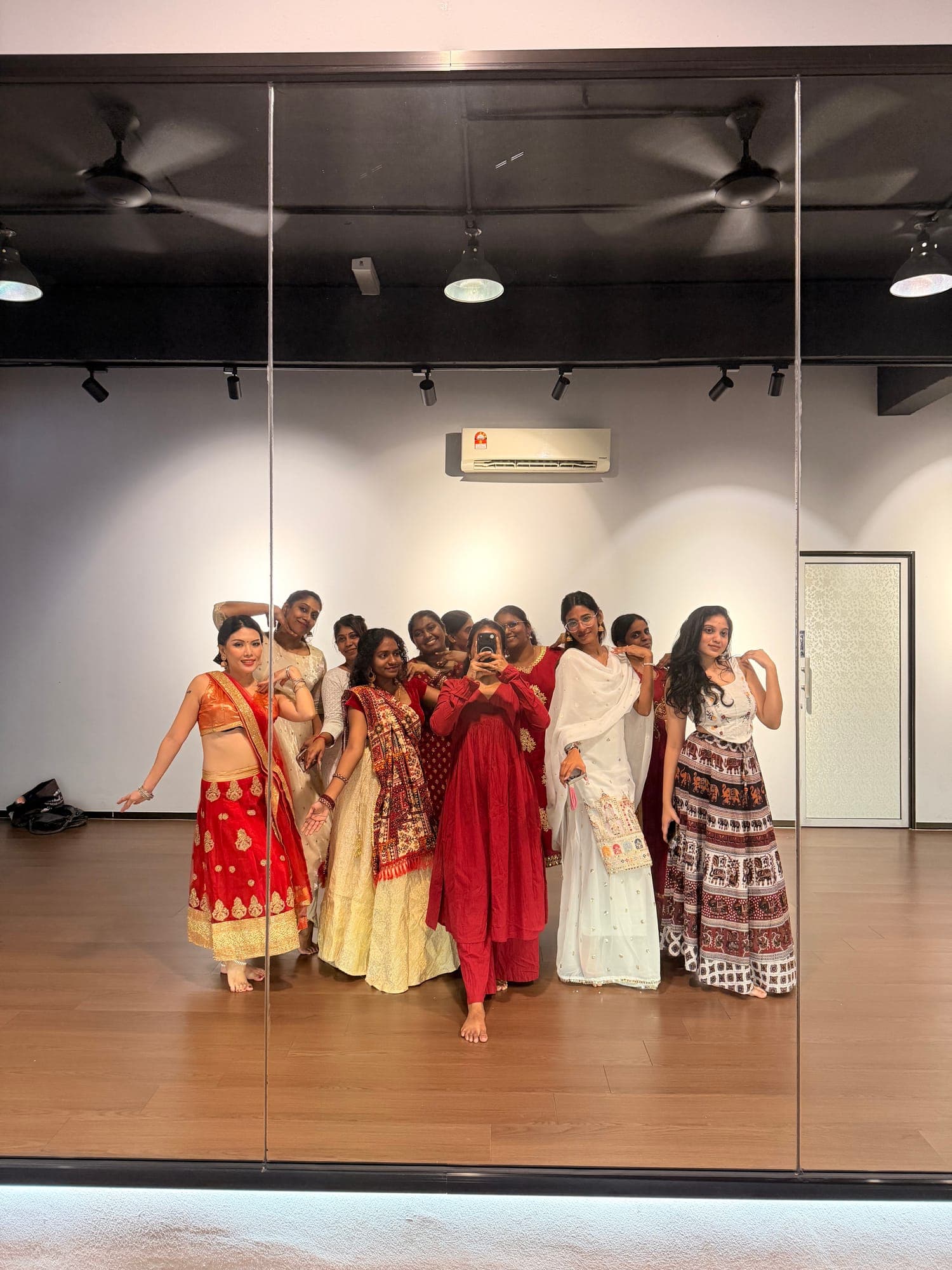 Dancers in colourful traditional skirts and dresses posing in a mirrored studio in Georgetown